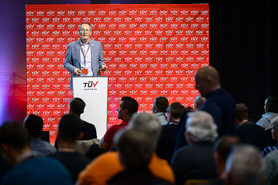 Mann steht am Rednerpult und spricht zum Publikum.