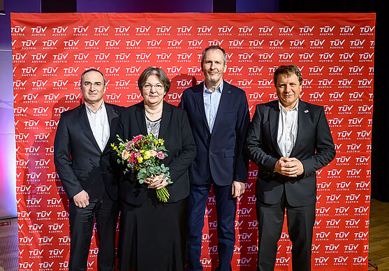 Drei Männer und eine Frau mit Blumenstrauß.