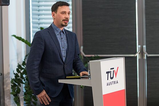 Manuel Jarc (Caverion Österreich GmbH) sprach über die Implementierung von Energiemesssystemen in öffentlichen Einrichtungen und Immobilien: Praxisbeispiele, KI-Integration, Quick Wins<br /> Mann mit Hemd und Sakko hinter einem Rednerpult.