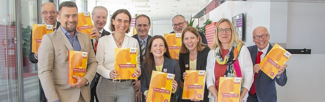 Gruppenfoto: Mitarbeiter:innen halten das Kursprogramm in den Händen