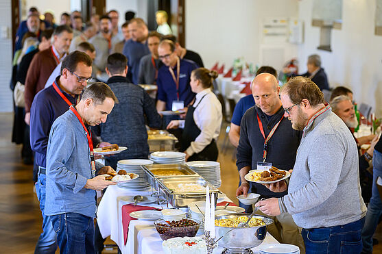 In der Mittagspause erwartete die Teilnehmer:innen ein reichhaltiges Buffet.<br /> Menschen an einem Buffet.