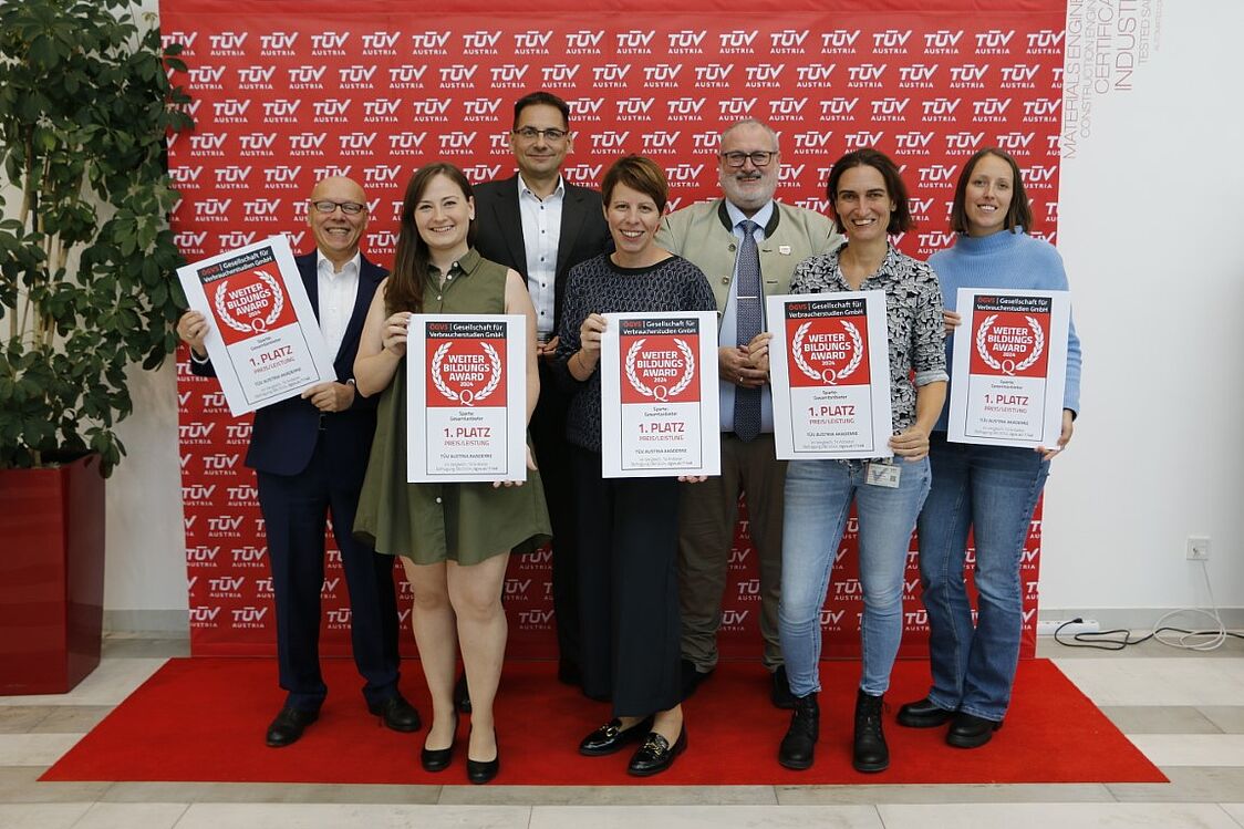 Gruppenfoto mit Männern und Frauen der TÜV AUSTRIA Akademie, die den Weiterbildungsaward hochhalten.