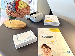 Modell eines menschlichen Gehirns, Notizzettel und das Jahrbuch Weiterbildung auf einem Tisch.