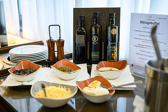 Schmackhafte Schmankerl trafen auf...<br /> Stilleben von einer Menükarte, Schalen mit Kürbiskernen und Käse, Pfeffermühlen und Kürbiskernöl.