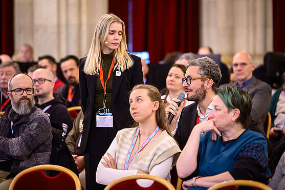 Herr aus Publikum spricht in Handmikrofon.