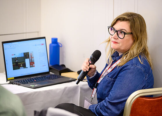Dame sitzt vor Laptop und spricht in Mikrofon.