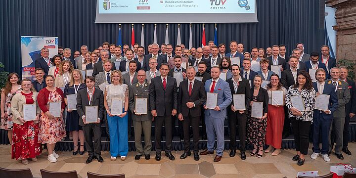 Großes Gruppenfoto aller Graduierten mit den Diplomen in der Hand