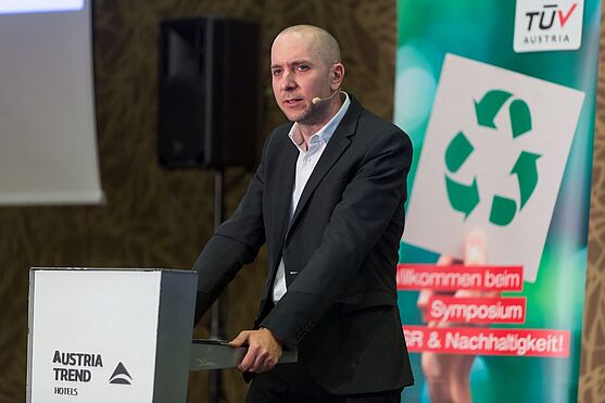 Ein Mann im schwarzen Anzug stützt sich auf das rednerpult. Christian Richter-Schöller ist Rechtsanwalt und redet über Recht in der Nachhaltigkeit.