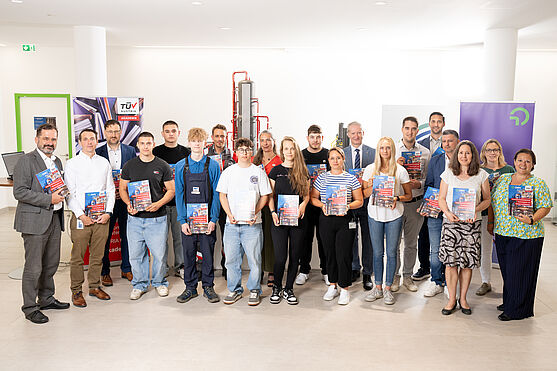 Gruppenbild mit mehreren Personen am Bild, von Lehrlingen der Chemieverfahrenstechnik, über das Autorenteam bis hin zu CEO TÜV AUSTRIA und Direktor der OMV