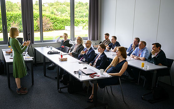 DI Ingrid Heinz (TÜV AUSTRIA GmbH) lieferte hilfreiche Informationen zum Thema Verfahrensbeschleunigung mit nichtamtlichen Sachverständigen.<br /> Dame in Seminarraum spricht zu Publikum