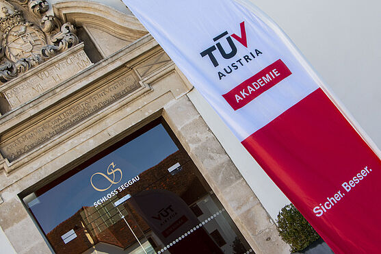 Eingang Schloss Seggau. Im Vordergrund eine TÜV AUSTRIA Akademie Beachflag.