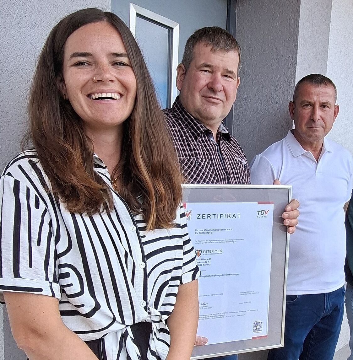 (vlnr): Tina Reiterer, Peter Mies, Thomas Seidel <br /> Eine Frau und zwei Männer lachen in die Kamera. Einer der beiden Männer hält ein Zertifikat in den Händen
