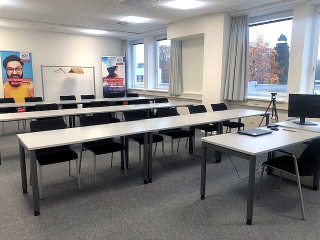 Beispiel Seminarraum in Salzburg<br /> Ein moderner Seminarraum mit Sesseln und Tischen, die zu einem einzelnen Referenten-Pult ausgerichtet sind.