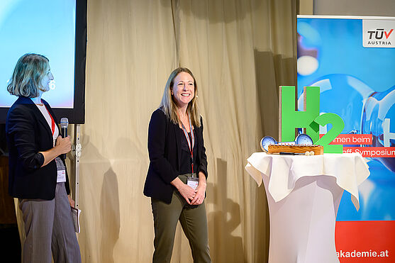 Sarah Neumann (Bundesministerium für Wirtschaft, Energie und Tourismus) widmete sich dem Thema Wasserstoff im Hochlauf: Vorhaben und Aktivitäten des BMWET.<br /> Dame hält Vortrag
