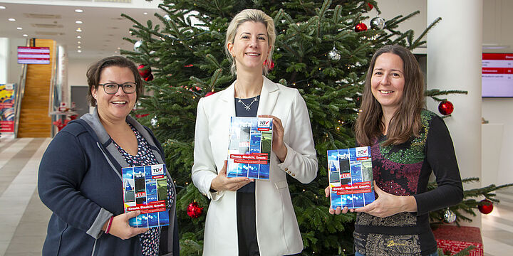 Drei Damen vor einem Weihnachtsbaum. Sie halten das Buch "Einsatz. Blaulicht. Gesetze." in den Händen