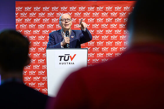 Mann am Rednerpult spricht in Mikrofon.