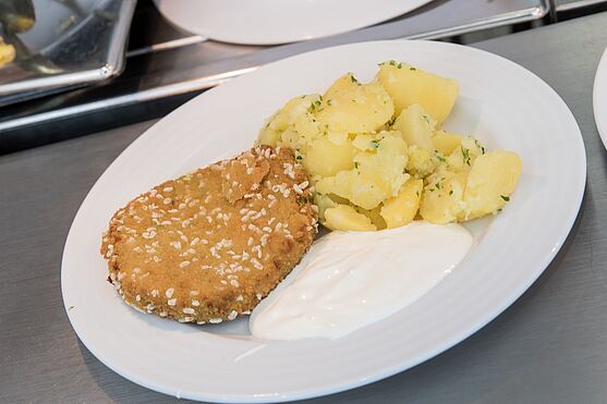 Panierter Fisch mit Erdäpfeln und Sauce.