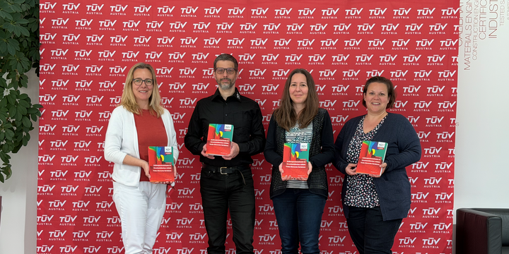 4 Personen, 3 Frauen und 1 Mann, stehen vor einer roten Logowand und halten das Cover des neuen Buches in die Kamera