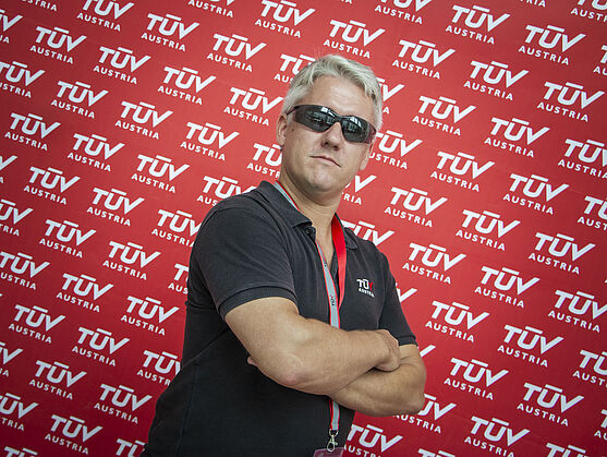 <br /> Herr mit Sonnenbrille posiert mit ernster Mine vor Pressewand.