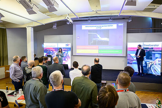 Nach guten Träumen von der F1 war der Einstieg in den nächsten Tag nicht allzu hart: Quiz it like you weld it! <br /> Eine Gruppe von Leuten grübelt vor einer Videowall. Darauf steht die Frage: Warum ist Vorwärme bei gewissen Stählen wichtig?