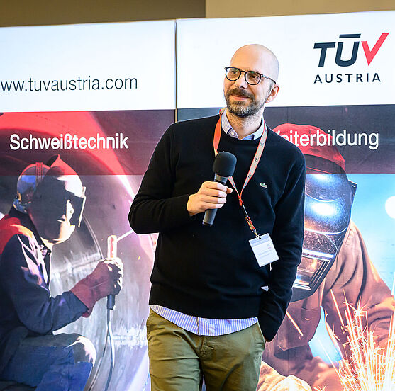 Zum Ende des ersten Tages gab es noch interessante Infos von Wolfgang Wilke (TÜV AUSTRIA HOLDING AG). AI 4 NDT: Künstliche Intelligenz in der Zerstörungsfreien Prüfung.<br /> Ein Mann mit Bart und Brille redet in ein Mikrofon.