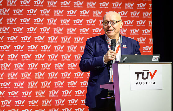 Bevor es mit den ersten Vorträgen losging, gab es noch ein paar freundliche einleitende Worte von Christian Bayer (TÜV AUSTRIA Akademie).<br /> Mann hinter Rednerpult mit Handmikrofon.
