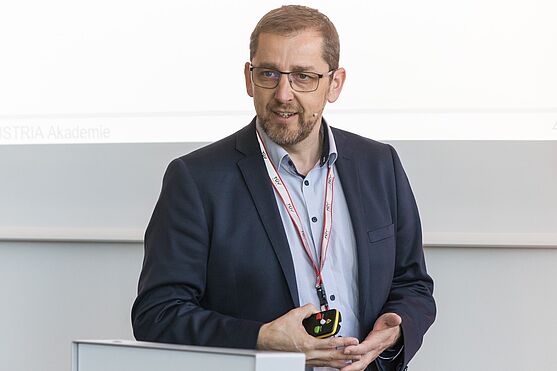 Mann in Hemd und Sakko hält Präsentation.
