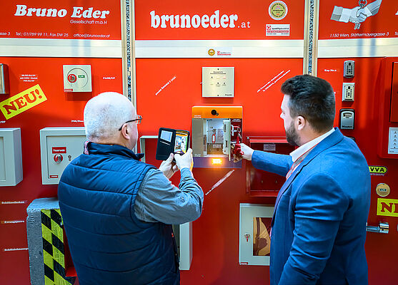 Ausstellerstand. Mann macht Foto mit seinem Handy.