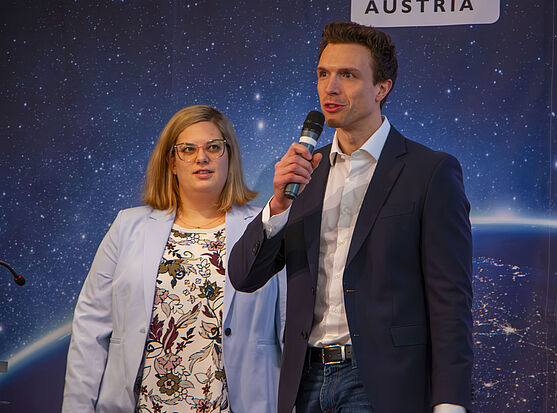 Der nächste Tag begann mit einem Vortrag von Katharina Wöhrer und Jan Waldner (OMV Downstream GmbH). Sie erklärten den IWE-Lehrgang aus Sicht ehemaliger Teilnehmer:innen.<br /> Dame und Herr auf der Bühne.