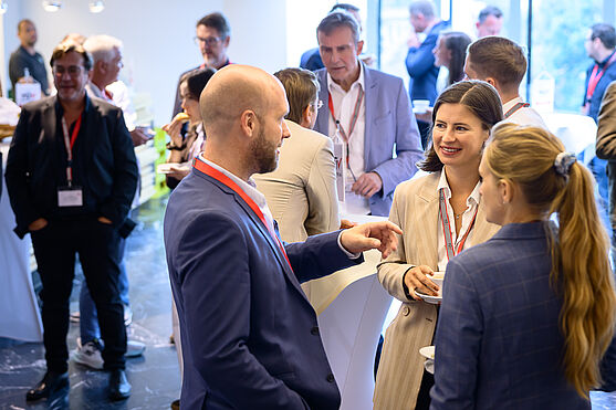 Fröhliches Netzwerken am TÜV AUSTRIA Wasserstoff-Symposium.<br /> Menschen unterhalten sich in der Pause
