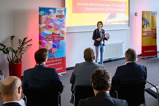 Dame steht vor Leinwand und spricht zum Publikum.