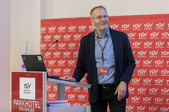 Martin Schmutzer (TÜV AUSTRIA AKADEMIE GBMH) eröffnete die Veranstaltung mit ein paar einleitenden Worten und einer herzlichen Begrüßung.<br /> Mann steht hinter Rednerpult auf einer Bühne.