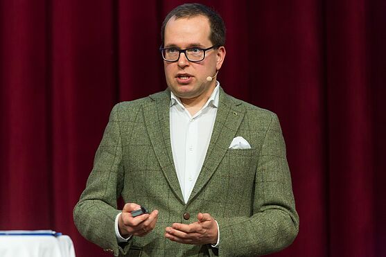 Im Anschluss sprach Alan Szwajkowski, EFS Unternehmensberatung über den digitalen Produktpass.<br /> Mann mit Brille, Hemd und Sakko mit Einstecktuch hält Vortrag.