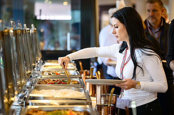 Dame bedient sich an einem Buffet.