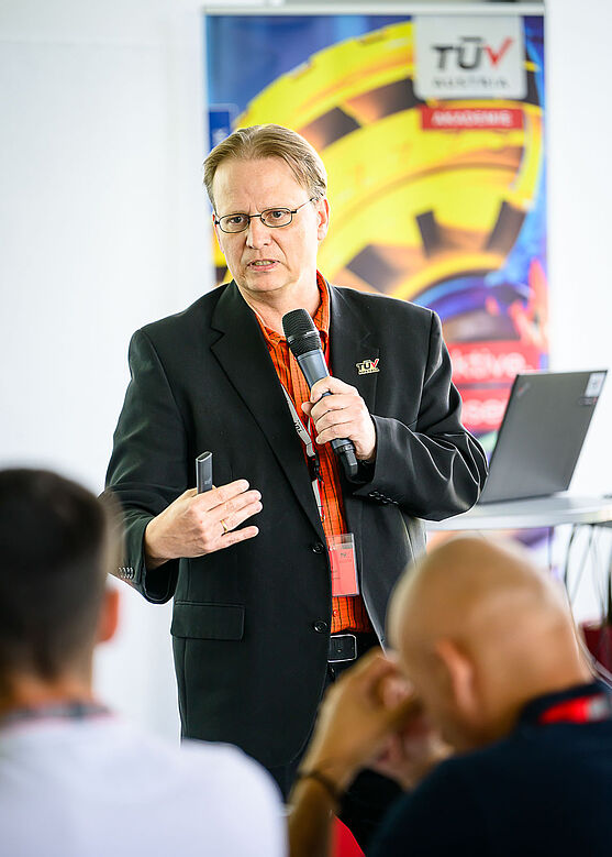 Weiter ging es mit BM DI Andreas Kloiber (TÜV AUSTRIA EXPERT SERVICES GMBH): Energie und Gebäudetechnik: Aktuelle Anforderungen der OIB 6<br /> Mann mit Handmikrofon spricht zu Publikum