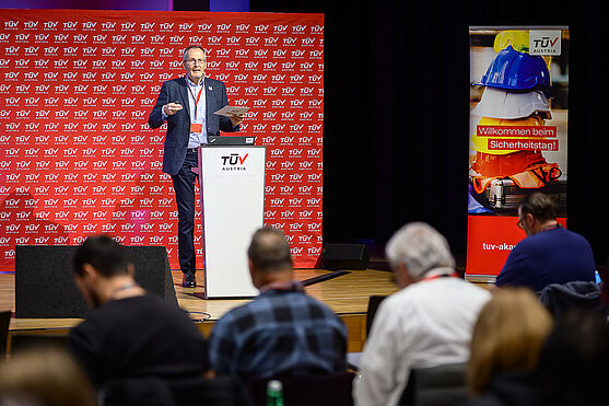 Martin Schmutzer (TÜV AUSTRIA Akademie) begrüßte in seiner Eröffnungsrede die Teilnehmer:innen herzlich zum Sicherheitstag in der Burg Perchtoldsdorf und Online.<br /> Mann auf Bühne hält Vortrag.