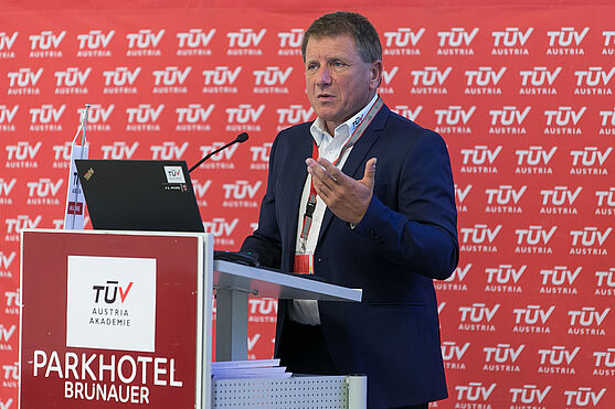 SV Ing. Martin Swoboda EUR ING (TÜV AUSTRIA) informierte über den Umgang mit Abweichungen von Normen im Bauwesen und die Konsequenzen für den Brandschutz.<br /> Mann hält Präsentation.