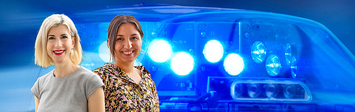 Zwei freundlich lächelnde Damen. Im Hintergrund Blaulicht.
