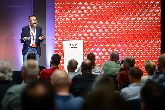 Mann hält Vortrag auf Bühne.