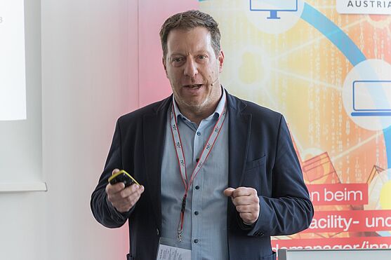 Herr im Sakko hält Präsentation.