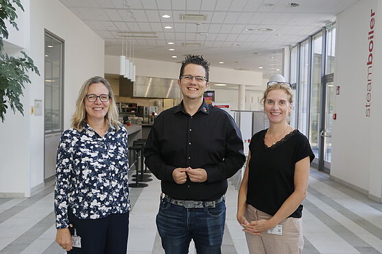 Zwei Frauen und ein Mann stehen nebeneinander. 