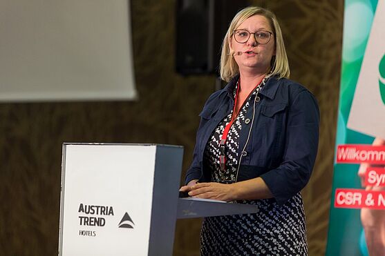 Patricia Kals, eine blonde Frau in einem blauen Business-Kostüm, referiert über die Wesentlichkeitsanalyse und den Nachhaltigkeitsbericht.