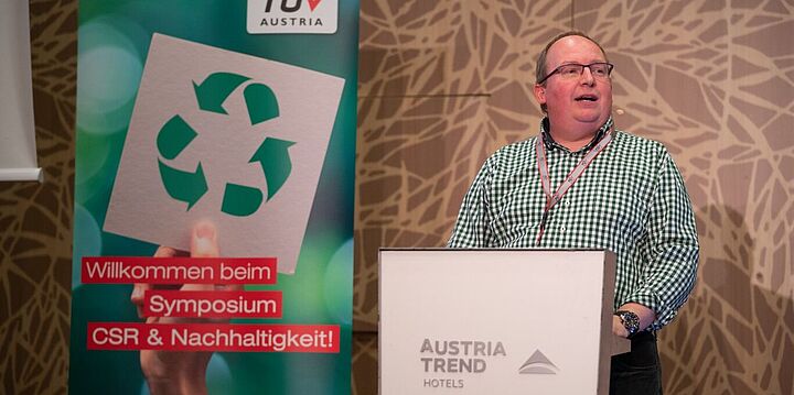 Mann hält Vortrag auf Bühne.