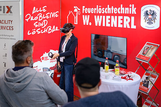Bei den Ausstellerständen gab es in den Pausen unter anderem auch die Möglichkeit, Neuheiten im Bereich Brandschutz selbständig zu testen!<br /> Dame mit VR Brille am Ausstellerstand von Feuerlöschtechnik W. Wienerl.