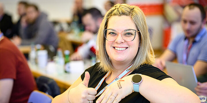 EIne blonde Frau mit Brille. Auf ihrem linken Handrücken hat sie ein Tattoo mit der Aufschrift Welding X-treme.