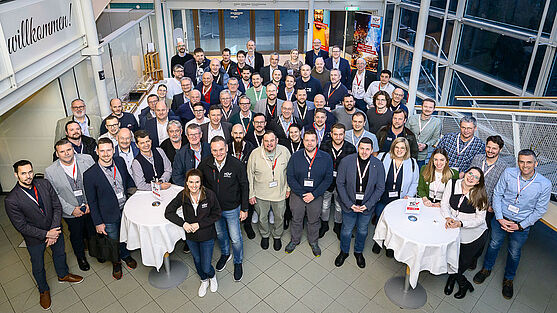 Ein Gruppenfoto läutete die Abendveranstaltung ein:<br /> Gruppenbild von 30 Leuten, die in die Kamera lächeln.