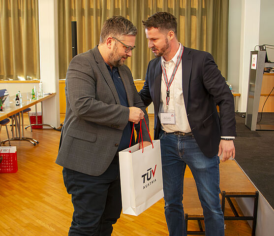 Die Preisverleihung an den schnellsten Fehlersucher am Mikroskop bildete den gelungenen Abschluss der Veranstaltung.<br /> Zwei Männer mit TÜV AUSTRIA Akademie Sackerl.
