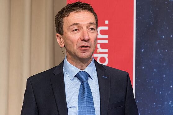 Herr im Anzug hält Vortrag.