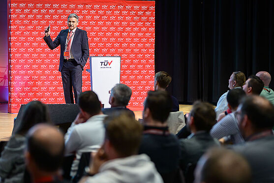 Mann auf Bühne spricht zum Publikum.