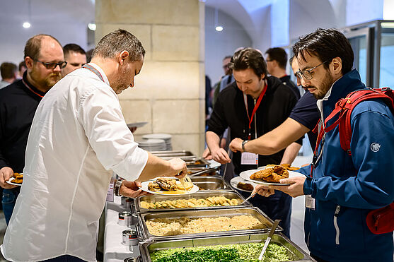 Männer holen sich Speisen vom Buffet.